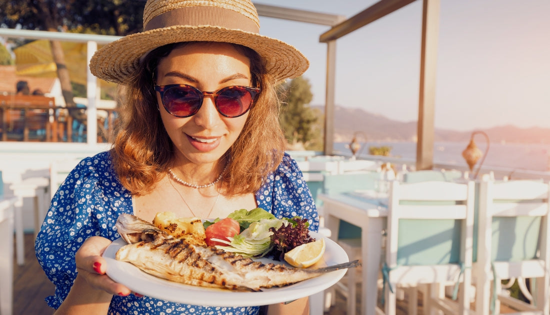 Woman on the water eating a variety of fish and vegetables